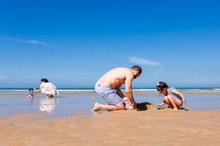 O pai a fazer castelos de areia com a filha