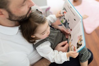 O pai lê um livro com a filha ao colo