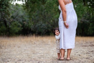 Uma criança escondida atrás da perna da mãe