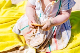 Mãos pequenas com uma bolacha cheia de areia