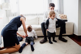 A mãe calça as meias ao filho na sala